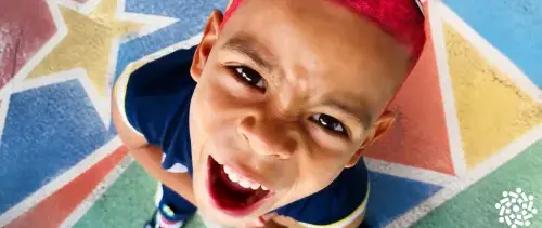 Menino com cabelo vermelho olha para cima com cara de bravo. Quando a criança quer fazer as próprias escolhas, muitos pais ficam divididos entre deixar e proibir. Ajude-a a aprender a escolher