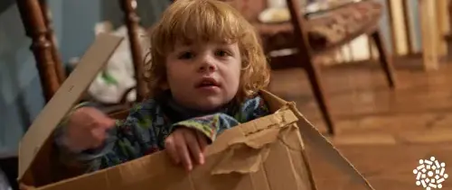 Criança pequena cria sua brincadeira usando caixa de papelão